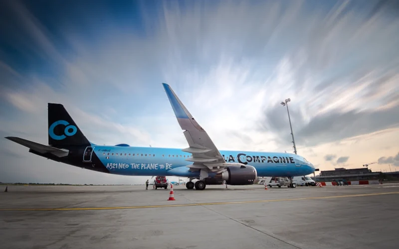 Blue La Compagnie Airbus A321neo parked on the tarmac with ground crew and orange cones nearby at an airport