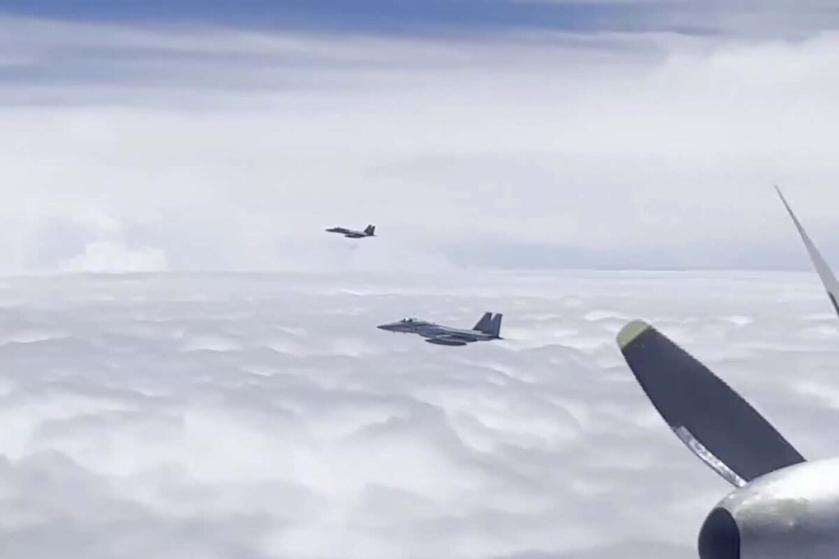 Two F 15 type fighters shadow a Russian aircraft during the joint patrol as seen from onboard the Russian formation Two fighter jets flying in formation above white clouds seen from a passenger plane window with part of another wing in view
