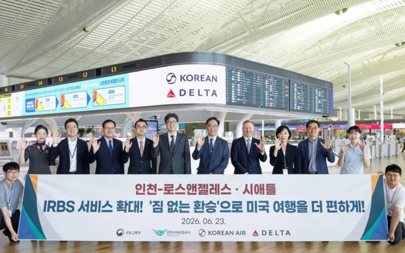 Group of professionals at an airport holding a large banner with Korean Air and Delta logos visible date 20260623 and flight information boards in the background