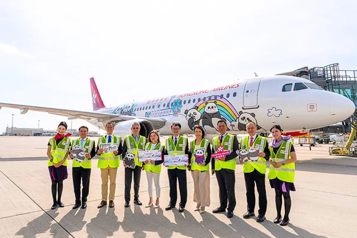 Group of airline staff in neon vests posing in front of a panda themed Hong Kong Airlines plane on the tarmac