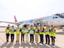 Group of airline staff in neon vests posing in front of a panda themed Hong Kong Airlines plane on the tarmac
