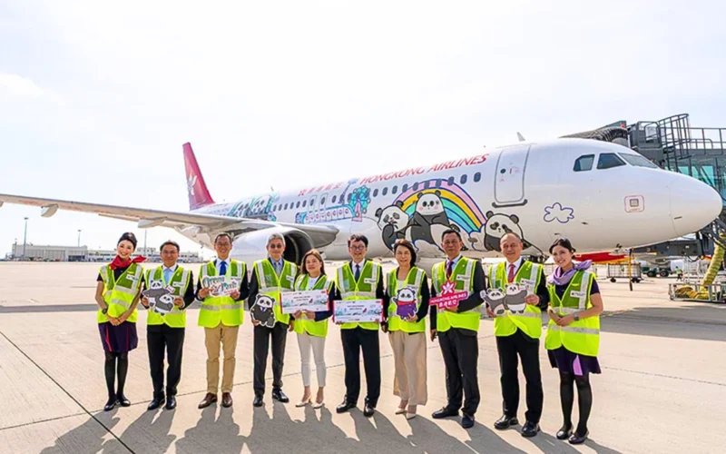 Group of airline staff in neon vests posing in front of a panda themed Hong Kong Airlines plane on the tarmac