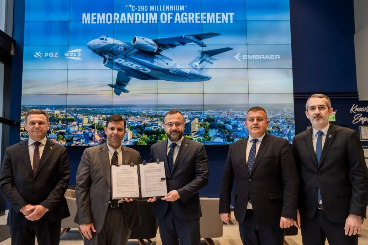 Five men in suits pose with a signed memorandum of agreement in front of a large blue backdrop displaying a cargo aircraft and a city skyline