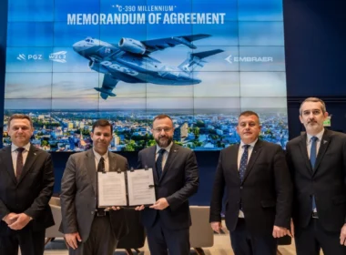 Five men in suits pose with a signed memorandum of agreement in front of a large blue backdrop displaying a cargo aircraft and a city skyline.