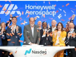 Group of diverse executives celebrating on a Nasdaq stage with orange confetti and a blue Honeywell Aerospace backdrop