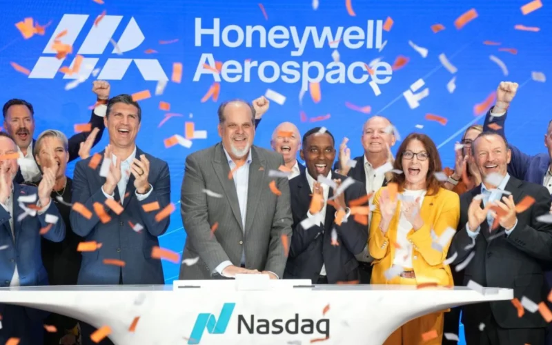 Group of diverse executives celebrating on a Nasdaq stage with orange confetti and a blue Honeywell Aerospace backdrop