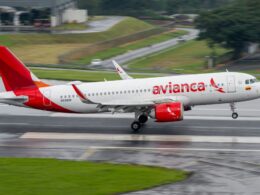 Avianca passenger jet taxiing on a wet runway red tail and logo visible