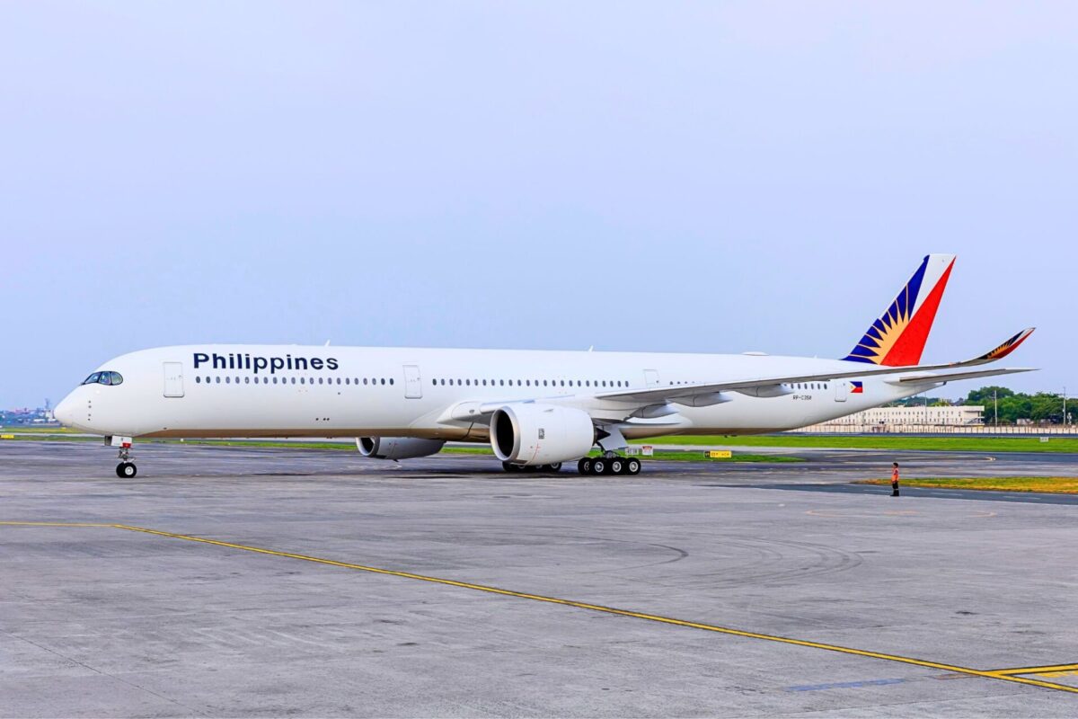 Philippine Airlines passenger aircraft on a taxiway with a colorful red blue and yellow tail logo under a clear sky