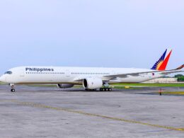 Philippine Airlines passenger aircraft on a taxiway with a colorful red blue and yellow tail logo under a clear sky