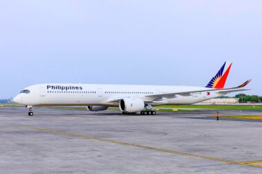 Philippine Airlines passenger aircraft on a taxiway with a colorful red blue and yellow tail logo under a clear sky