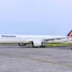 Philippine Airlines passenger aircraft on a taxiway with a colorful red blue and yellow tail logo under a clear sky