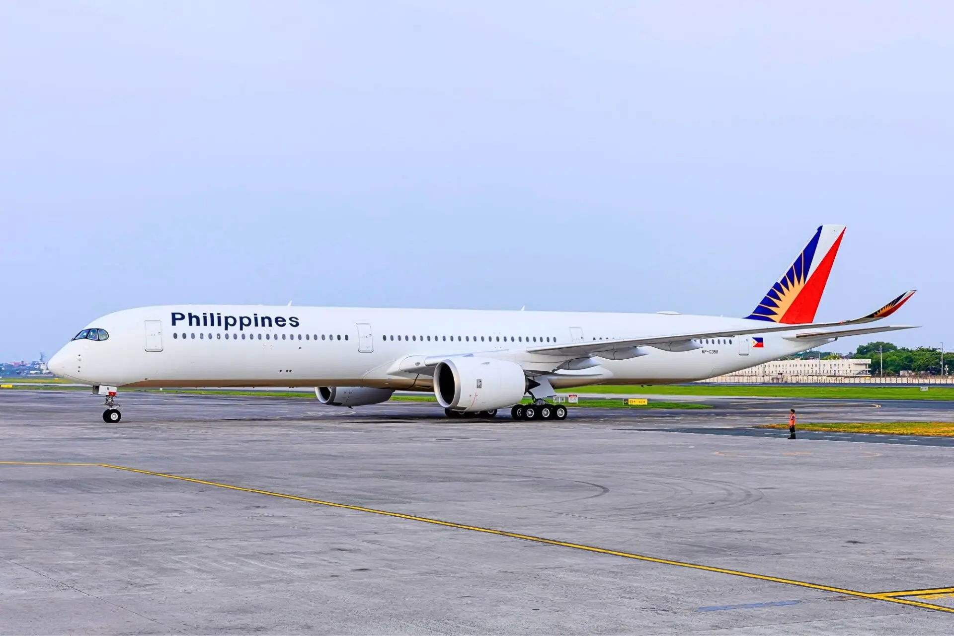 Philippine Airlines passenger aircraft on a taxiway with a colorful red blue and yellow tail logo under a clear sky
