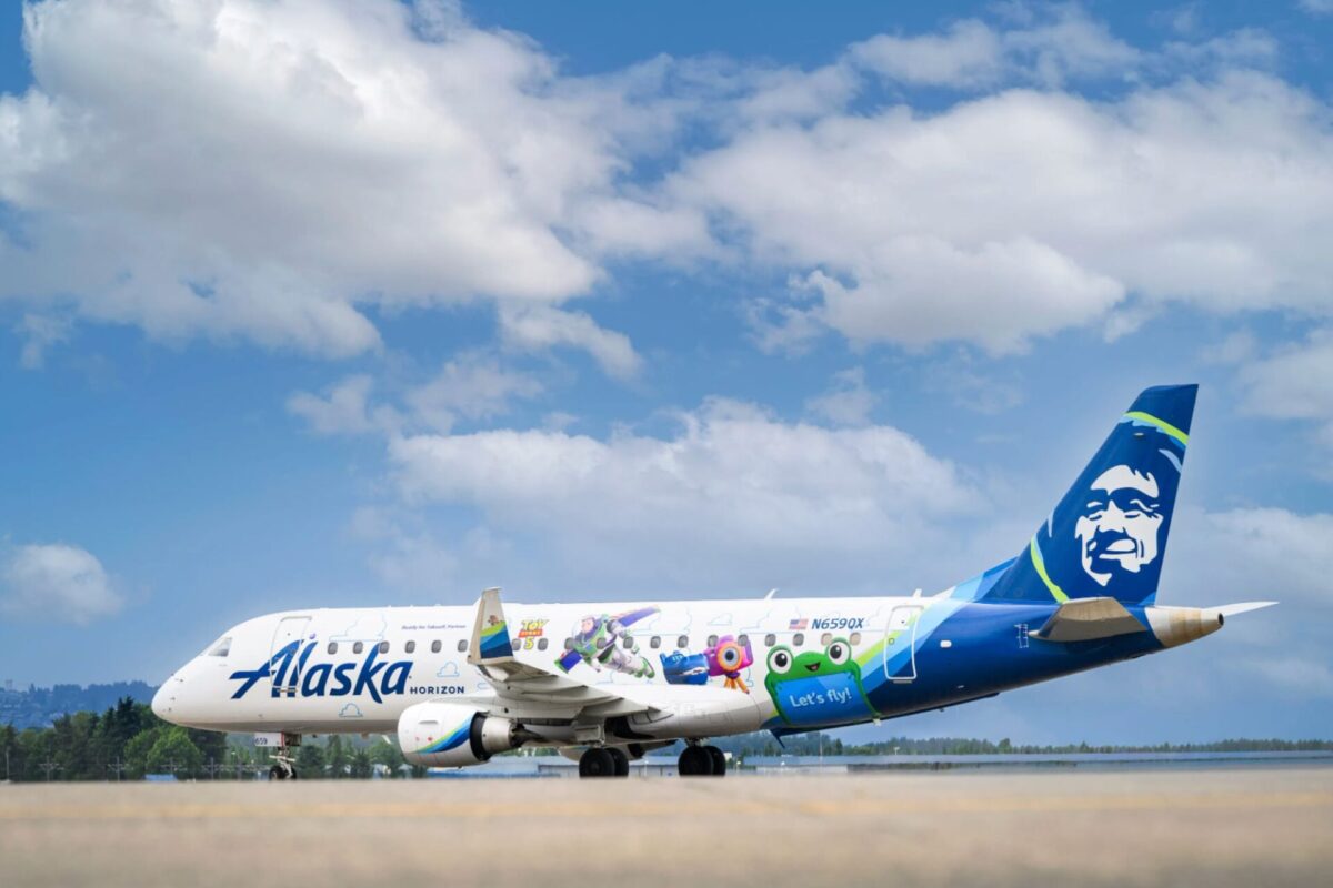 Alaska Horizon passenger plane with colorful character themed livery on the runway blue sky and tail with a smiling mascot logo