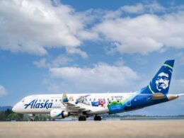 Alaska Horizon passenger plane with colorful character themed livery on the runway blue sky and tail with a smiling mascot logo