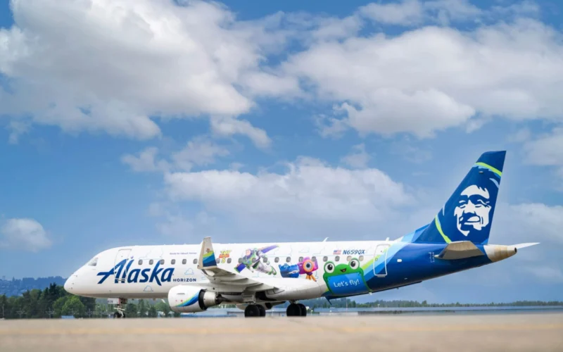 Alaska Horizon passenger plane with colorful character themed livery on the runway blue sky and tail with a smiling mascot logo