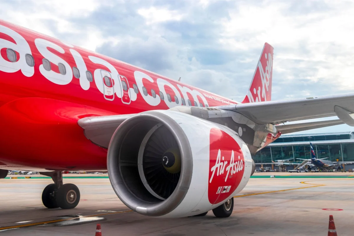 AirAsia aircraft on tarmac with large red fuselage and engine in foreground at an airport gate area