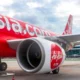 AirAsia aircraft on tarmac with large red fuselage and engine in foreground at an airport gate area