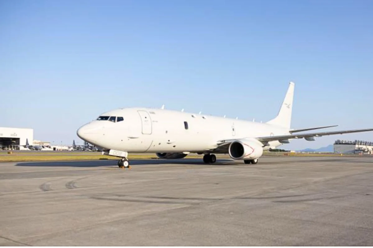 White passenger airliner parked on the airport tarmac with a clear blue sky above it nose pointing left