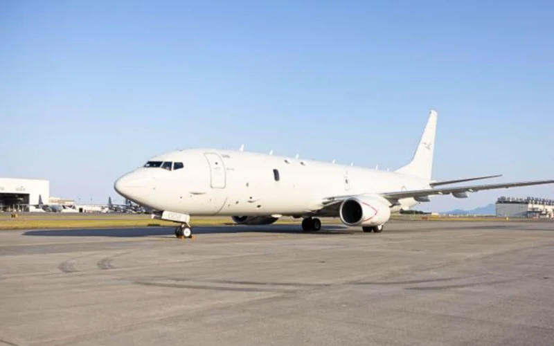 White passenger airliner parked on the airport tarmac with a clear blue sky above it nose pointing left