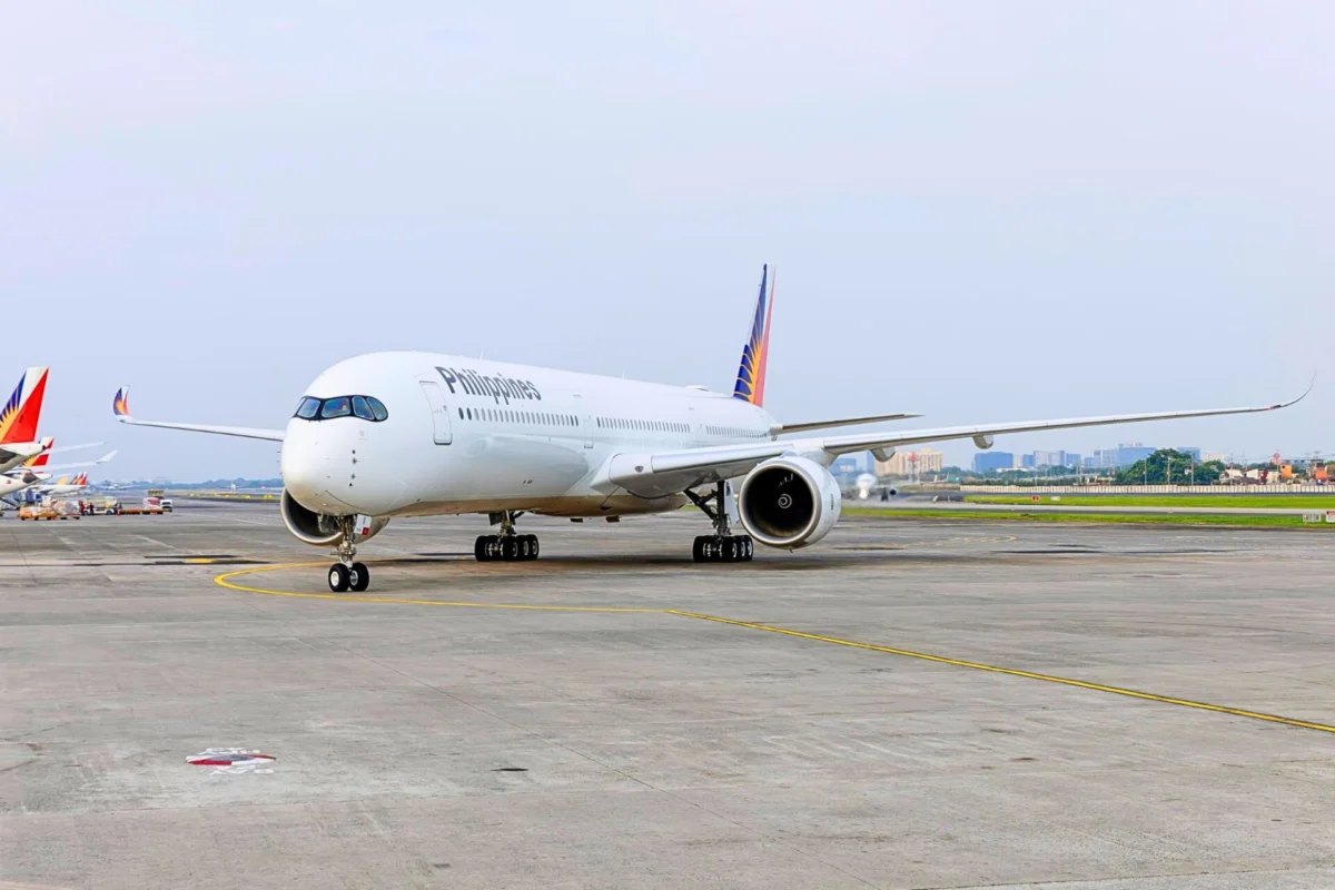 White Philippines airliner parked on the taxiway with a colorful tail design in the background on a sunny day at the airport