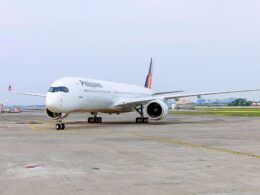 White Philippines airliner parked on the taxiway with a colorful tail design in the background on a sunny day at the airport