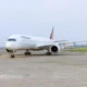 White Philippines airliner parked on the taxiway with a colorful tail design in the background on a sunny day at the airport