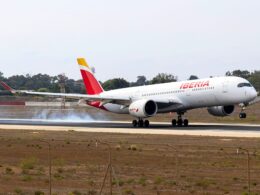 Iberia narrow body airplane on a runway with ground smoke tail fin in yellow and red preparing for takeoff or landing roll
