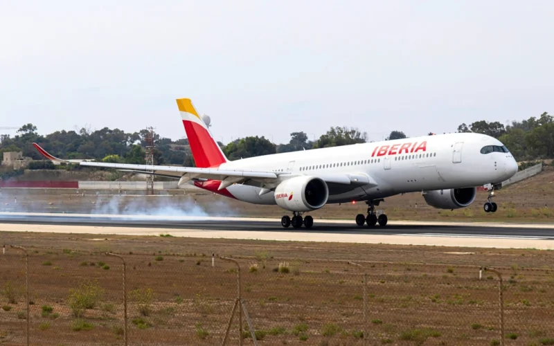 Iberia narrow body airplane on a runway with ground smoke tail fin in yellow and red preparing for takeoff or landing roll