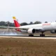 Iberia narrow body airplane on a runway with ground smoke tail fin in yellow and red preparing for takeoff or landing roll
