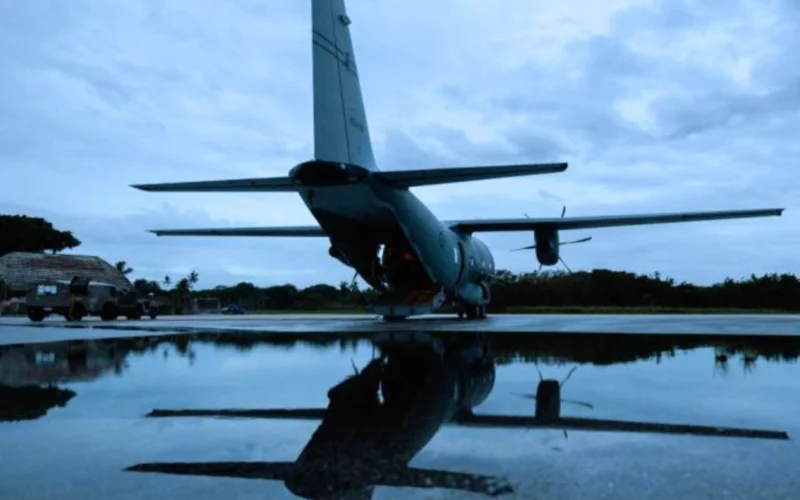 Rear view of a military transport aircraft C 130 on a runway wings spread reflected in a wet surface