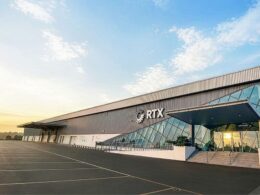 Modern RTX building with glass atrium and metal siding empty parking lot at sunrise