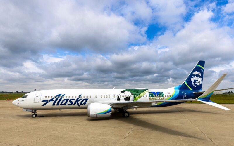 Alaska Airlines debuts World Cup 2026 livery on 737 9 MAX White Alaska Airlines jet on the tarmac with a colorful Seattle World Cup City liverie and tail art under a cloudy sky