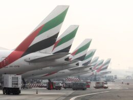 Row of Emirates airplanes parked at the gate showing their distinctive green red white and black tail designs
