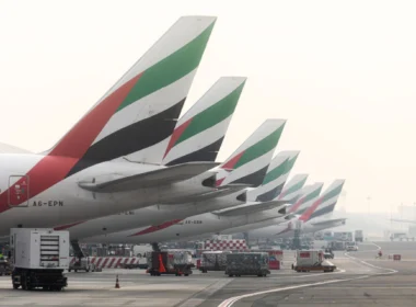 Row of Emirates airplanes parked at the gate, showing their distinctive green, red, white, and black tail designs