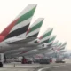 Row of Emirates airplanes parked at the gate showing their distinctive green red white and black tail designs