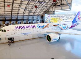 Airplane in a hangar with Moana themed livery and the word HAWAIIAN on the fuselage