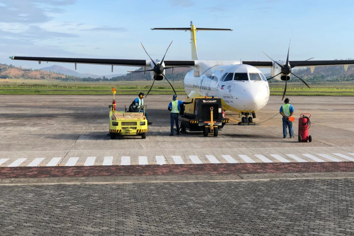 Cebu Pacific to move AirSWIFT flights under Cebgo from July White twin engine ATR style aircraft parked on the tarmac while ground crew in high visibility vests operate yellow support equipment nearby