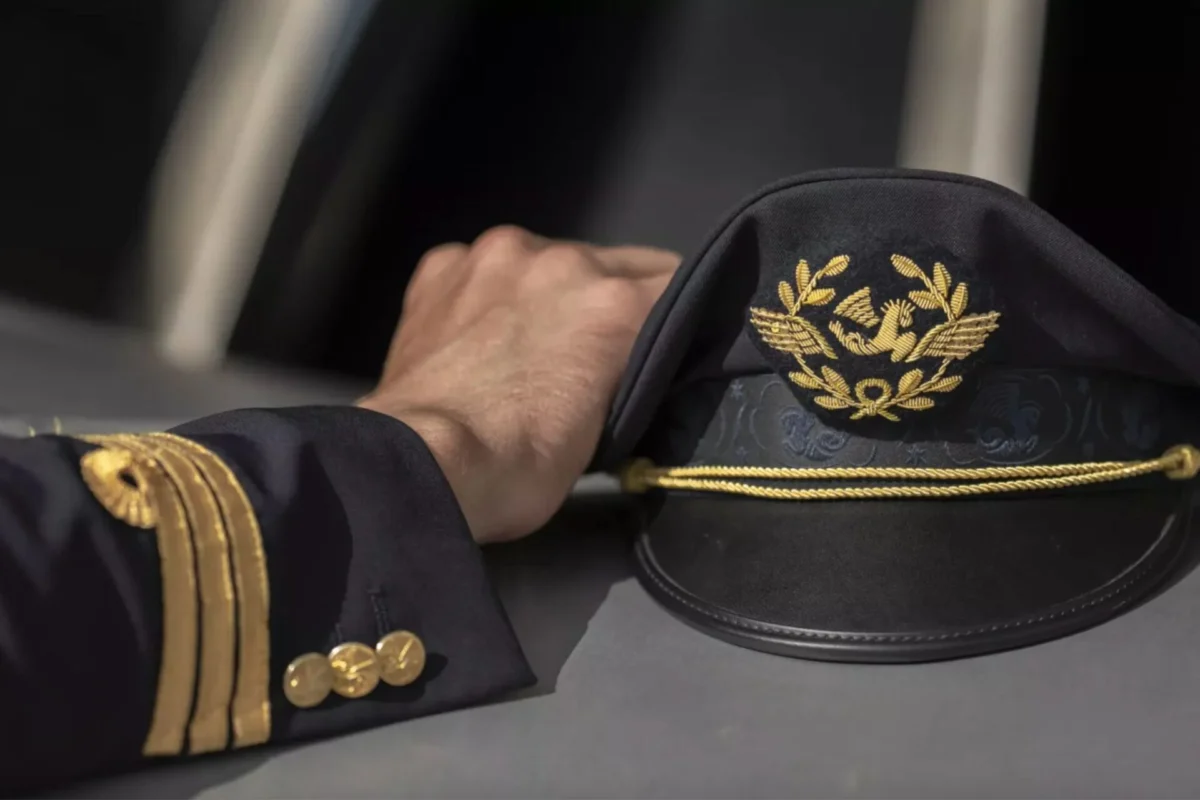 Air France launches 2026 Cadet Program recruitment Pilots hand rests on a dark captains hat with gold embroidery and braid detail on a table