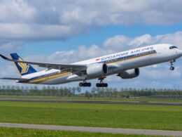 Singapore Airlines passenger jet lifting off the runway wheels still extended under a partly cloudy blue sky
