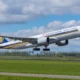 Singapore Airlines passenger jet lifting off the runway wheels still extended under a partly cloudy blue sky