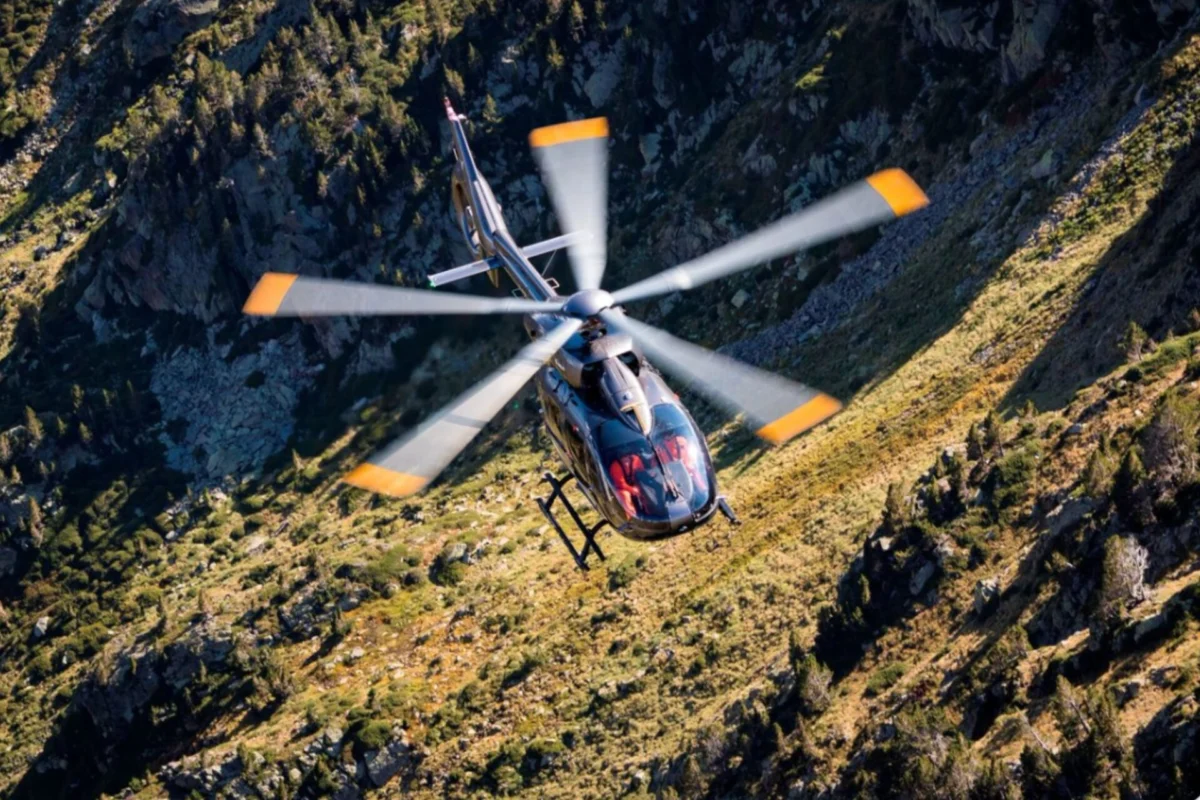 Armenia orders six H145s in first Airbus Helicopters deal A helicopter flying over a rocky mountain landscape viewed from above with spinning rotors and a grassy valley below during daylight