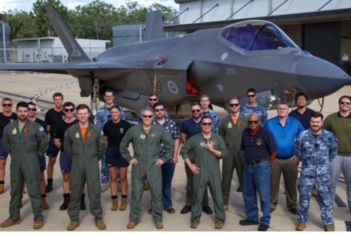 Australia US complete first joint F 35A weapons flight test Group of pilots and crew in green flight suits and blue uniforms posing in front of a gray fighter jet on a tarmac