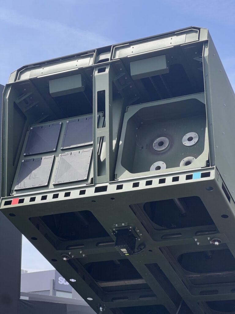 X Fire launcher canisters Open military missilerockets launcher pod with multiple panel doors and circular connector ports visible inside a green steel frame