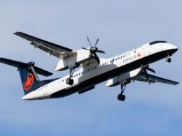 Air Canada Express turboprop in a white and dark blue livery taking off with landing gear down against a blue sky