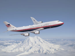 Air Force One presidential aircraft flying over a snow covered mountain range with clear blue sky