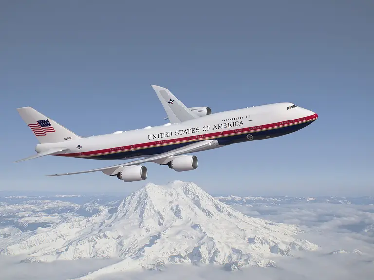 Air Force One presidential aircraft flying over a snow covered mountain range with clear blue sky