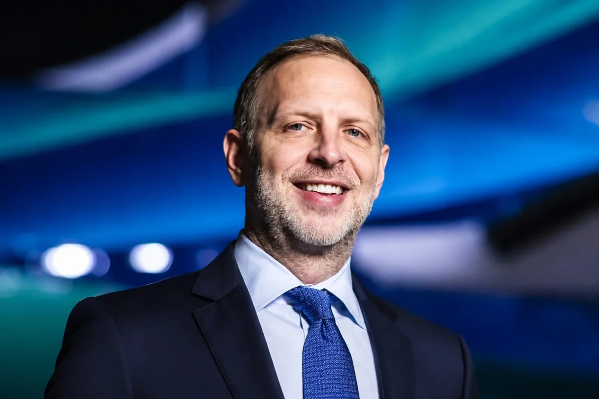 alaska32 Smiling middle aged man in a dark suit and blue tie with a blue lit blurred background