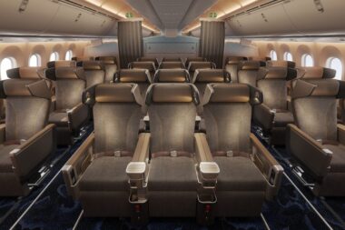 Interior of an airplane cabin with rows of brown leather seats armrests and windows along the sides