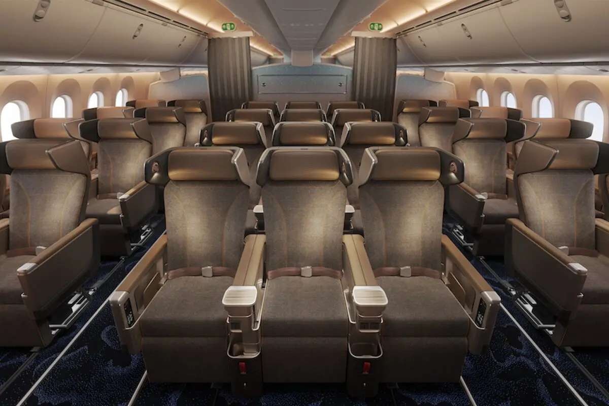 Interior of an airplane cabin with rows of brown leather seats armrests and windows along the sides