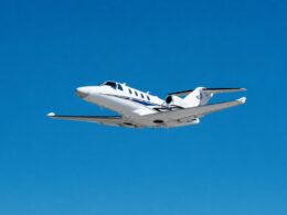 White private jet in flight against a clear blue sky